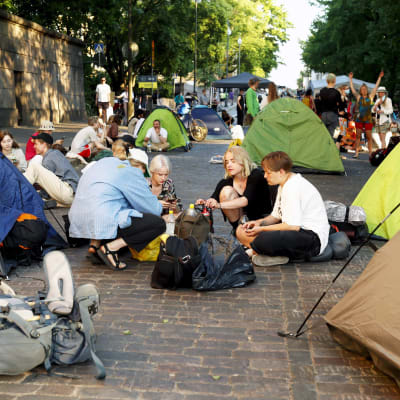 Demonstranter sitter på gatan bland tält.