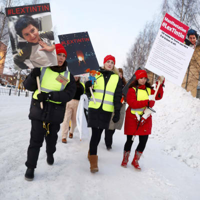Mielenosoittajat kantavat kylttejä ja kävelevät lumisessa maisemassa.