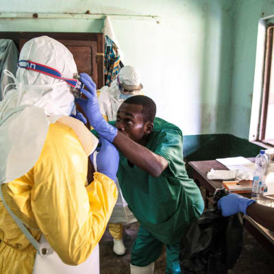 Hälsovårdare iklädd skyddsdräkt förbereder sig på att undersöka patienter som kan ha smittats av ebola. Sjukhus i Bikoro 13.5.2018. 