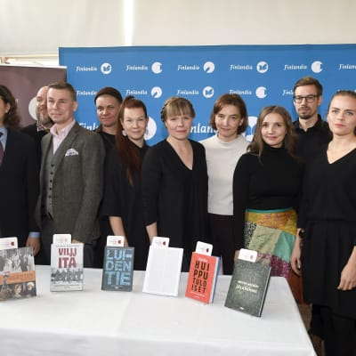 Kandidaterna för Fack-finlandiapriset 2019 står på rad bakom ett bord med deras böcker.