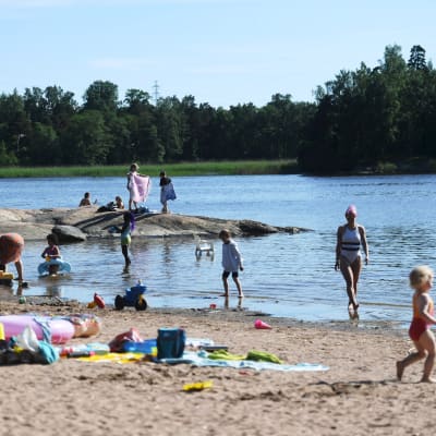 Människor leker och umgås vid sandstranden på Sandudden i Helsingfors.