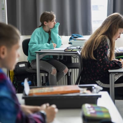 Tre danska elever sitter vid sina pulpeter. 