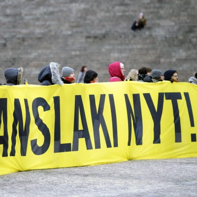 Demonstranter som bär upp en stor gul flagga med texten Translagen nu! 