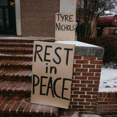 På två skyltar vid en trappa står det "Tyre Nichols" och "Rest in Peace" (Vila i frid). På marken intill finns ett tunt lager snö.