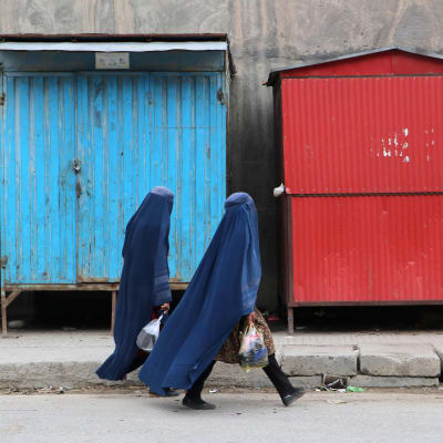 Afghanska burkaklädda kvinnor går längs en gata.