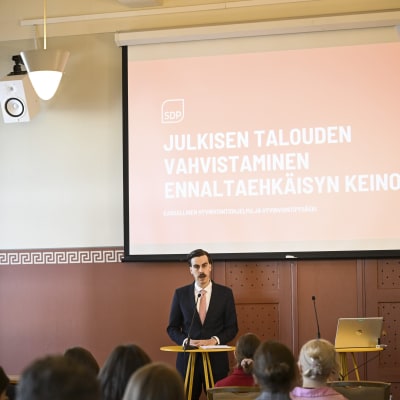 Matias Mäkynen framför en presentation om ett program med rubrik om att stärka den offentliga ekonomin genom preventiva åtgärder.