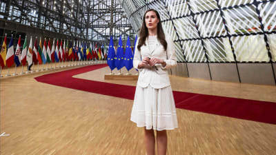 Sanna Marin i vit klädsel, hon träffar media inför ett EU-toppmöte i Bryssel