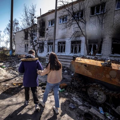 Kaksi nuorta katsoo tuhoutunutta koulurakennusta.