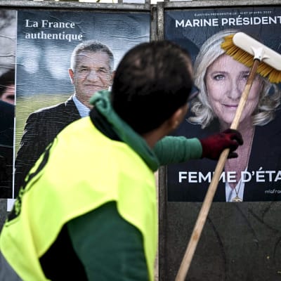 Työntekijä liisteröi julisteita ranskan presidenttiehdokkaista. 