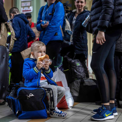 Pieni ukrainalainen lapsi syö juna-asemalla Puolassa.