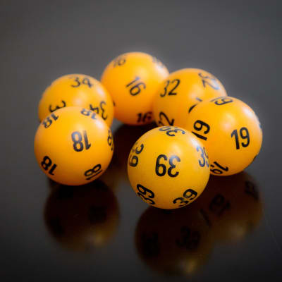 Kuusi keltaista lottoarvonassa käytettävän näköistä numeroitua palloa.