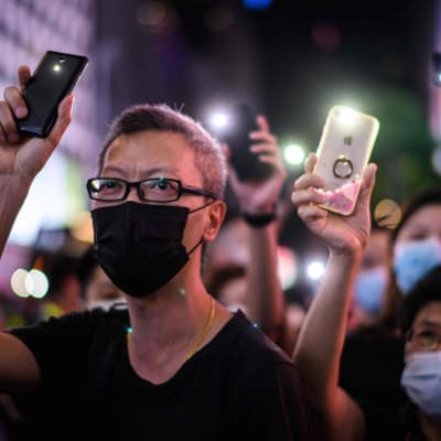 Demonstranter i Hongkong håller upp sina mobiler med mobilernas ficklampor tända.
