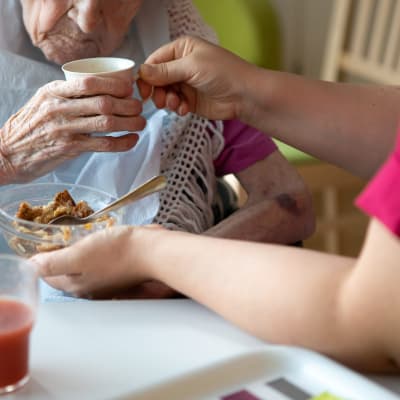 En vårdare hjälper en äldre klient att äta.
