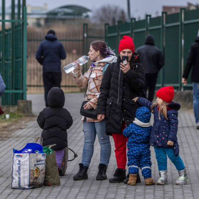 Människor står vid den polska-ukrainska gränsen, både barn och vuxna. 
