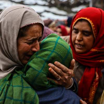 En gråtande kvinna kramar om en annan kvinna i en by i Indien efter att en av hennes kvinnliga släktingar mördades av sin man. 