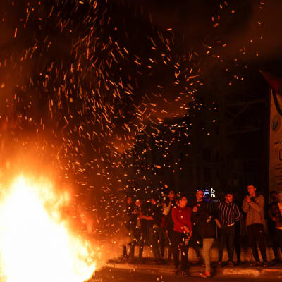 Ungdomar vid en  flammande eld på en mörk gata. 