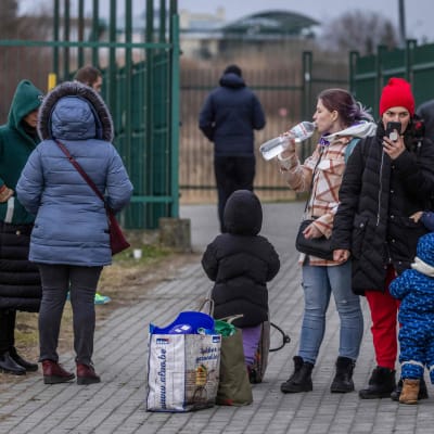 Människor står vid den polska-ukrainska gränsen, både barn och vuxna. 