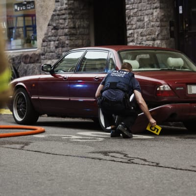 En polis utför en teknisk undersökning av en bil på platsen där en kvinna omkom och flera skadades då en person vansinneskörde i Helsingfors på fredagskvällen den 28 juli 2017.
