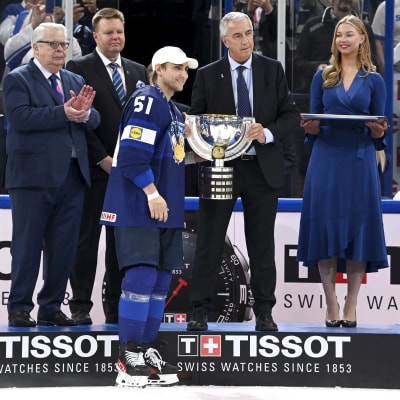 Valtteri Filppula hakee palkintopokaalia jääkiekon MM-kisojen finaalin jälkeen. Taustalla muun muassa Kalervo Kummola sekä kaksi mitalienjaossa avustanutta naista.