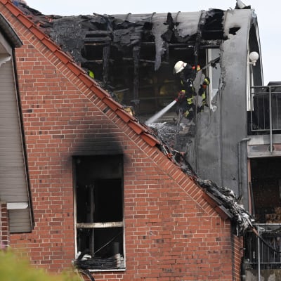 Palomies sammuttaa rakennusta, jonka katossa on suuri reikä.