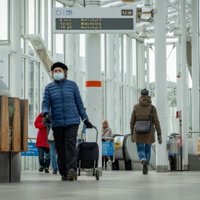 Människor på metrostationen i Nordsjö, Helsingfors. I förgrunden har en äldre kvinna munskydd.
