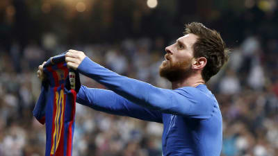 Lionel Messi håller fram sin tröja.