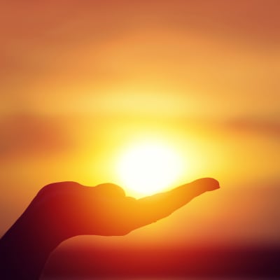 silhouette of a hand holding the sun