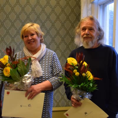 Helena Kari ja Ari Valkola hymyilevät kukkakimput kädessään.