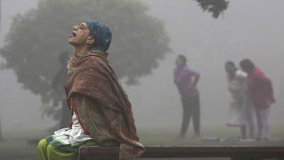 En kvinna utövar yoga i ett luftförorenad New Delhi.