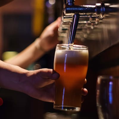 En servitör på en bar fyller ett glas med öl från en ölkran