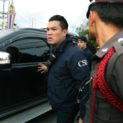 Den gripne tros vara inne i bilen som omges av thailändsk polis.