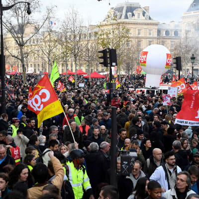 Hav av människor i Paris under jättedemonstration mot pensionsreform. Flera håller upp banderoller och flaggor.