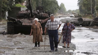 Lokalinvånare går förbi en förstörd Georgisk pansarvagn.