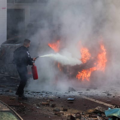 Israelin turvajoukkojen jäsen sammuttamassa autopaloa Askelonissa Israelissa.