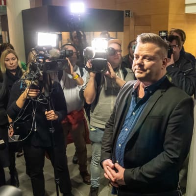 Jari Sillanpää Helsingin käräjäoikeudessa toimittajien piirittämänä.