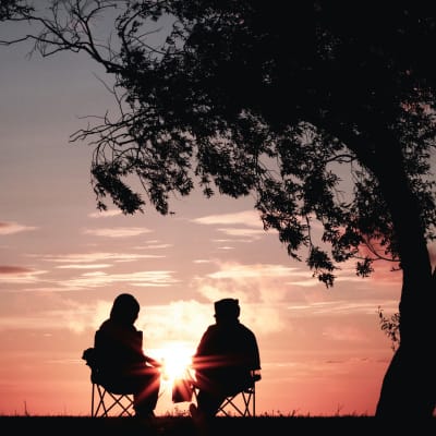 två personer sitter bredvid varann vid solnedgången