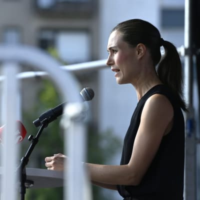 Statsminister Sanna Marin i profil när hon håller tal framför en rad med mikrofoner på torget i Lahtis.