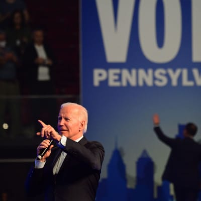 Joe Biden med mikrofon på en kampanjscen.
