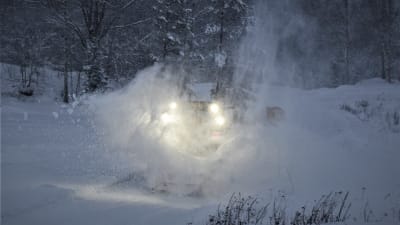 En traktor med snöplog och snö som ur omkring dem.