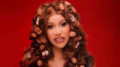Porträttbild av Cardi B, från musikvideon till låten "Up". Huvuden från Barbiedockor hänger i Cardi B:s lockiga hår.