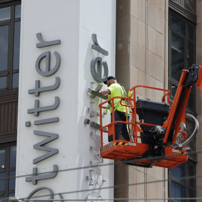 En byggarbetare monterar ner Twitters namn från huvudkontorets fasad i San Francisco. 