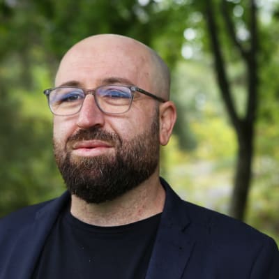 Mies seisoo puiden alla.