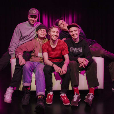 Viisihenkinen räp-yhtye Aarnikotkat sohvalla. Henkilöt vasemmalta oikealle: MC Pösö, Carlito, Santana, Rumilus ja Leo G
