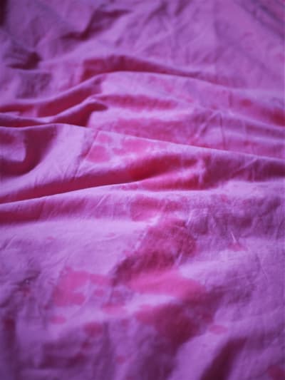 Blöta fläckar på rosa lakan.