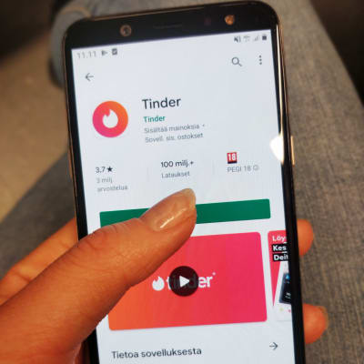 Kuvassa on puhelin, jossa käyttäjä aikoo ladata deittisovelluksen. 