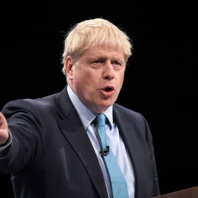 Boris Johnson i kostym, pekar sitt finger åt vänster.