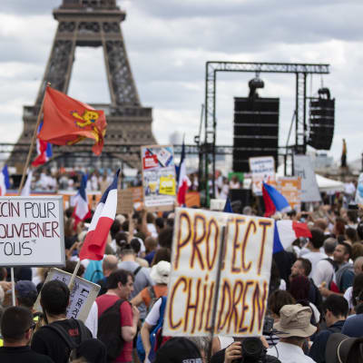Bild på en demonstration i Paris. På bilden syns en folkmassa där en del håller upp skyltar med franska slagord.