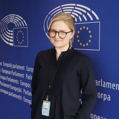 Bild på Marie Krogius som praktikant vid Europaparlamentet med EU:s flagga i bakgrunden 