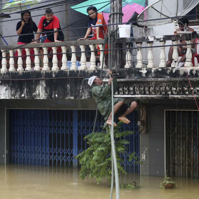 En man klättrar upp på en balkong på från en översvämmad gata i provinsen Nakhon Si Thammarat, i södra Thailand 6.1.2017