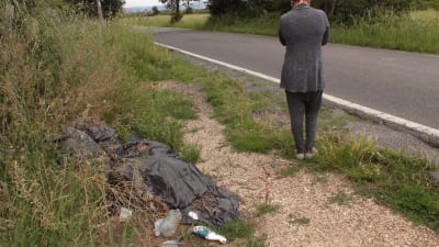 En kvinna med ryggen vänd mot fotografen vid en vägkant.
